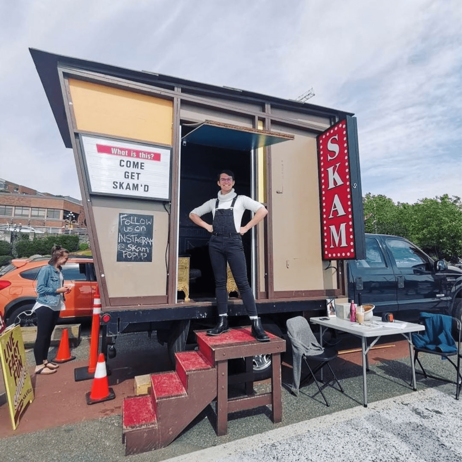 A young person, with their hands on their waist, grinning, standing in the doorway of a SKAM trailer.
